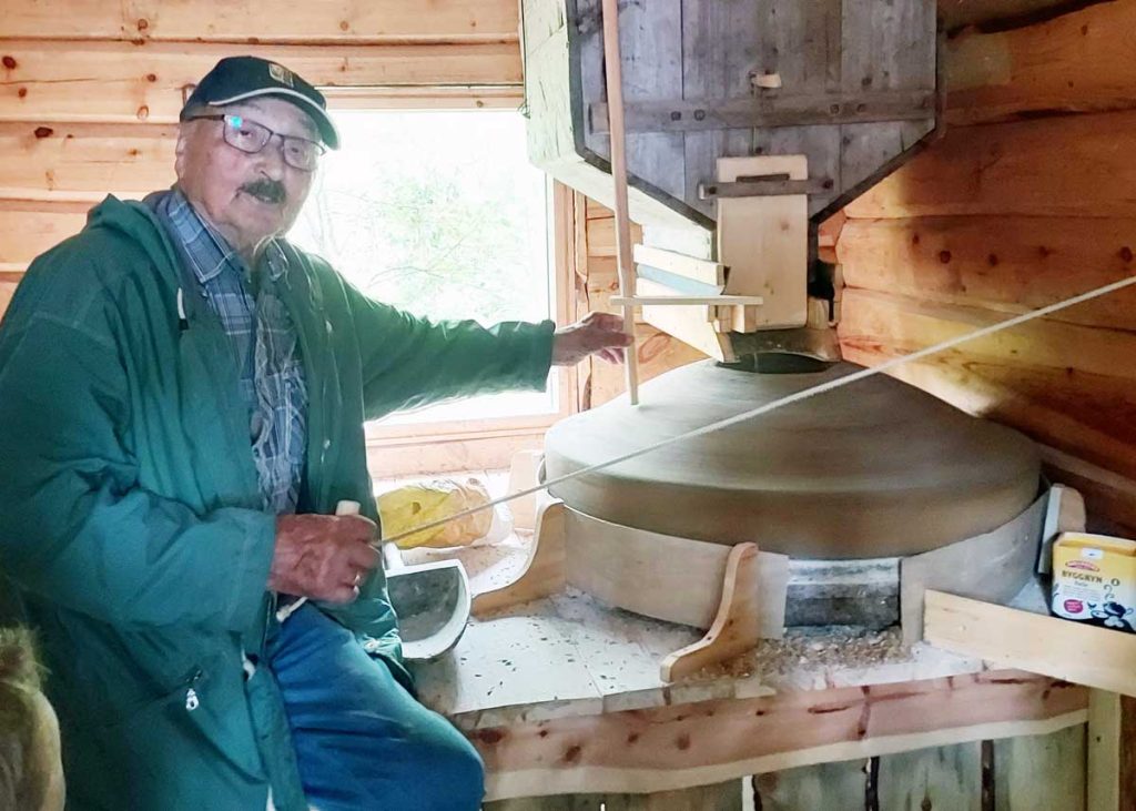 Gammel mann foran vannmølle